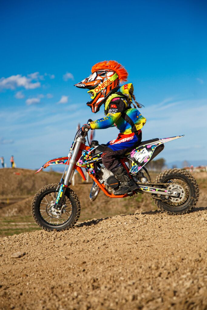 pexels-photo-19040842-19040842 Young racer on a dirt bike with helmet and gear, speeding on a gravel track.