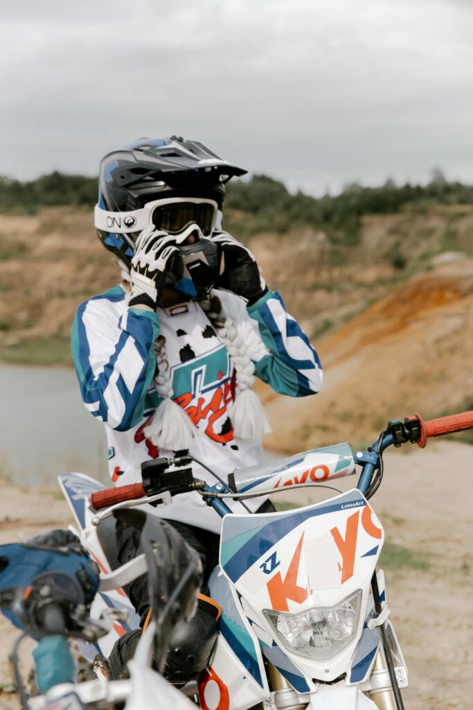Motocross rider adjusting helmet ready for an exciting off-road adventure in rugged terrain.